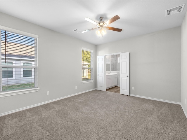 unfurnished bedroom with ensuite bathroom, carpet flooring, and ceiling fan