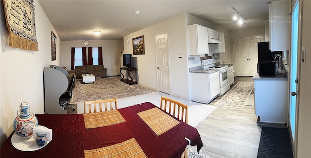 kitchen with light hardwood / wood-style floors, white cabinetry, white electric range, and black fridge