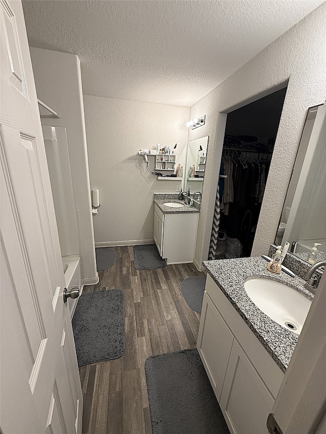 bathroom featuring vanity, a textured ceiling, wood-type flooring, and shower / bath combination