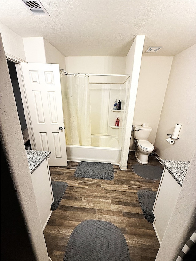 full bathroom featuring a textured ceiling, toilet, vanity, shower / tub combo with curtain, and hardwood / wood-style flooring