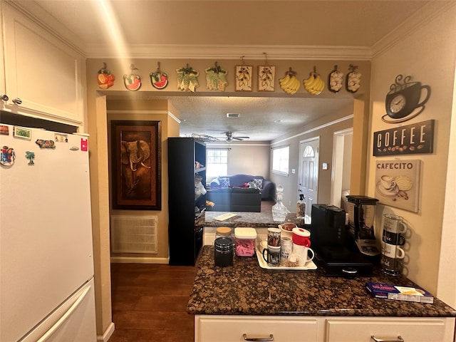 kitchen featuring white cabinetry, dark stone counters, ornamental molding, dark hardwood / wood-style floors, and white fridge