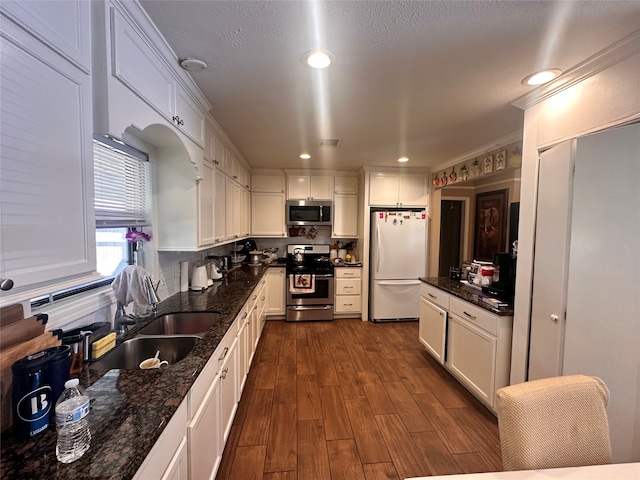 kitchen with dark wood-type flooring, appliances with stainless steel finishes, and white cabinetry