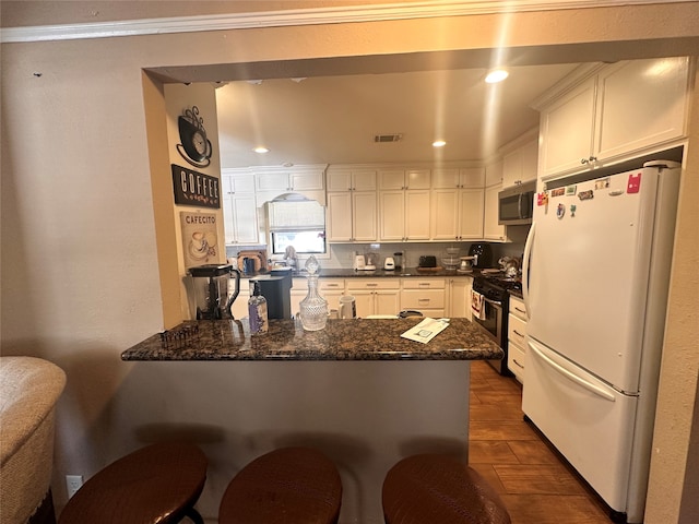 kitchen featuring appliances with stainless steel finishes, kitchen peninsula, white cabinets, and dark hardwood / wood-style flooring