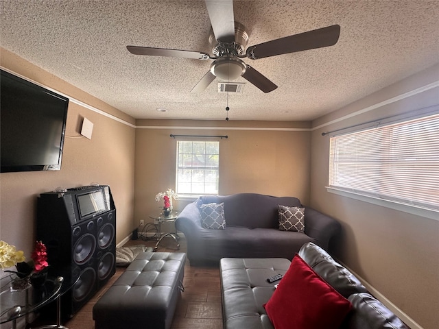 living room featuring ceiling fan, hardwood / wood-style flooring, and a textured ceiling