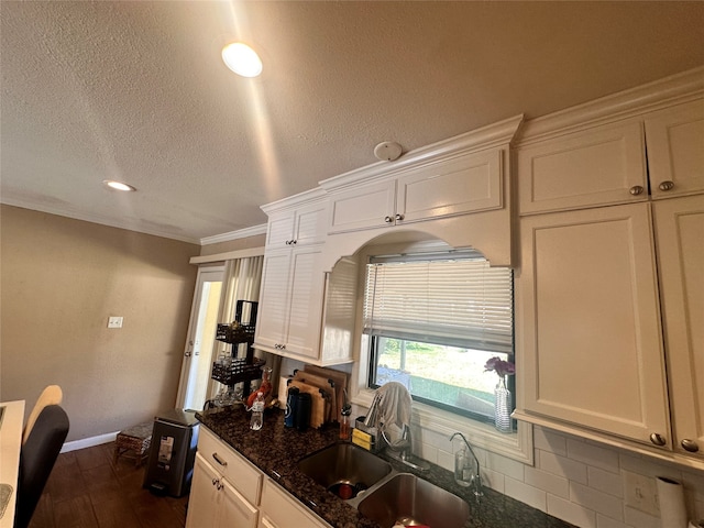 kitchen featuring sink, dark hardwood / wood-style flooring, white cabinets, dark stone countertops, and crown molding