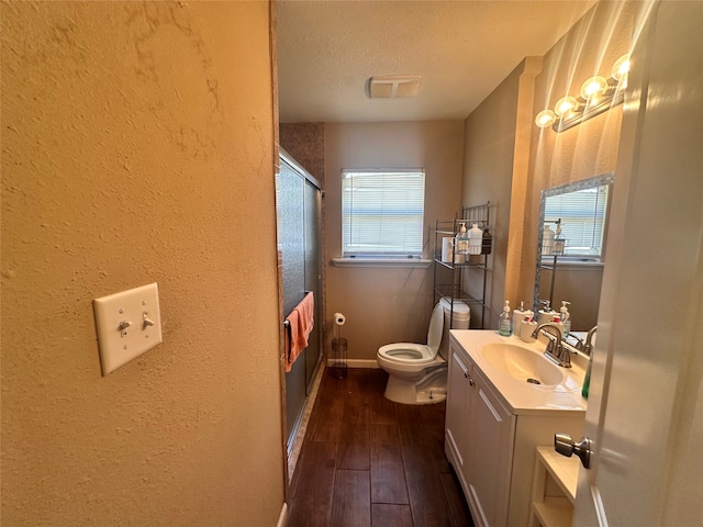 bathroom with toilet, hardwood / wood-style floors, vanity, a textured ceiling, and an enclosed shower