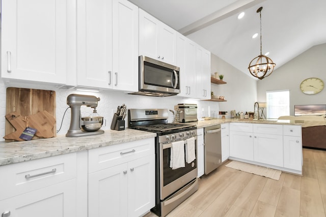 kitchen with vaulted ceiling, appliances with stainless steel finishes, light hardwood / wood-style floors, and white cabinets