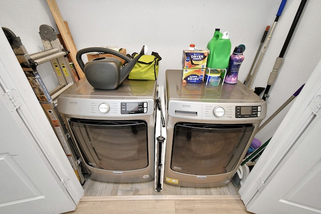 clothes washing area with washing machine and clothes dryer and hardwood / wood-style flooring