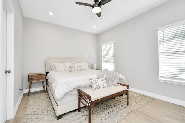 bedroom with baseboards, light wood-style flooring, and multiple windows