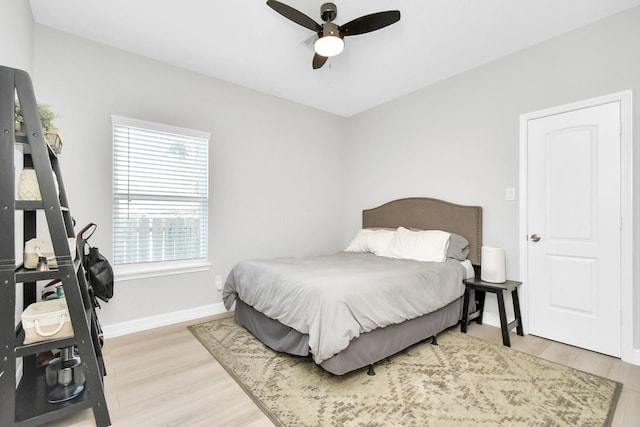 bedroom featuring baseboards, light wood-type flooring, and a ceiling fan