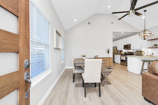 dining area with ceiling fan with notable chandelier, visible vents, high vaulted ceiling, and light wood-style floors