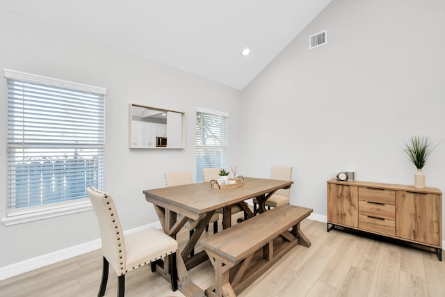 dining room with high vaulted ceiling and light wood-type flooring