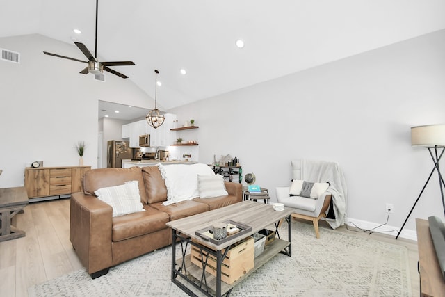 living room with high vaulted ceiling, light hardwood / wood-style flooring, and ceiling fan with notable chandelier