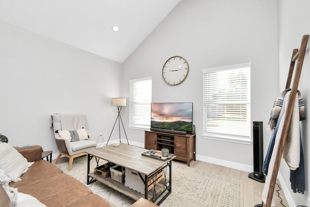 living area featuring high vaulted ceiling, light wood-style flooring, and baseboards