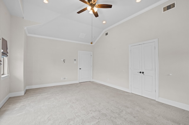 carpeted spare room featuring crown molding, vaulted ceiling, and ceiling fan