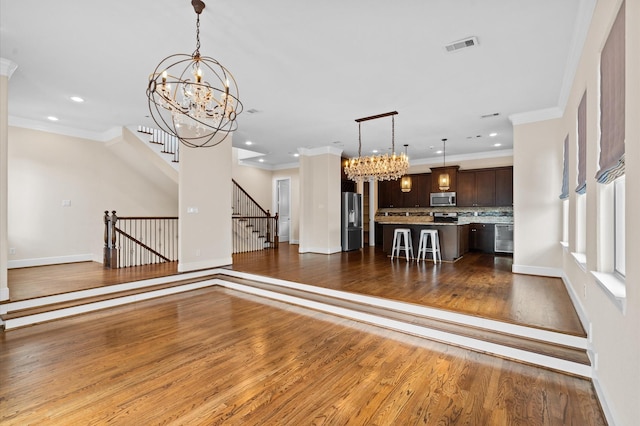 unfurnished living room with crown molding, dark hardwood / wood-style floors, and an inviting chandelier