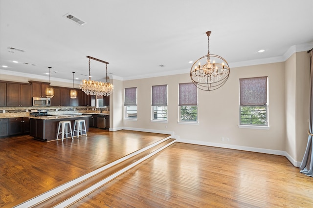 interior space with an inviting chandelier, ornamental molding, and light wood-type flooring