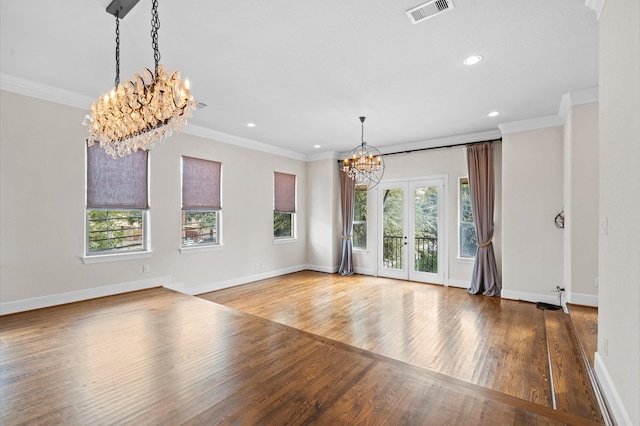 unfurnished living room featuring crown molding, an inviting chandelier, french doors, and light wood-type flooring