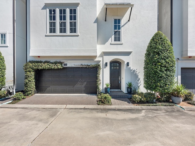 view of front of house featuring driveway, an attached garage, and stucco siding