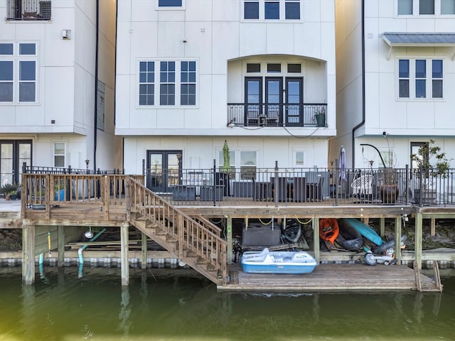 back of property with stairs, metal roof, and a water view