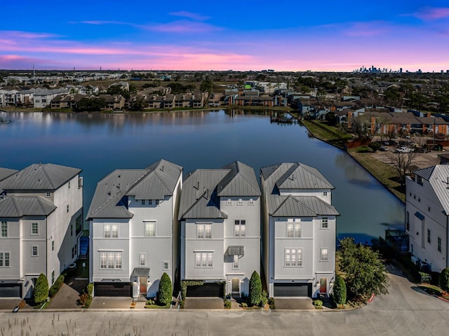 aerial view at dusk with a residential view and a water view