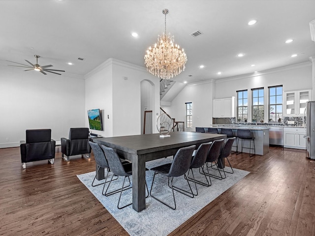 dining room featuring stairs, dark wood finished floors, visible vents, ornamental molding, and ceiling fan with notable chandelier