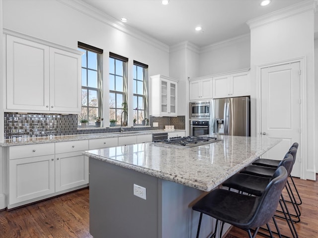 kitchen with tasteful backsplash, a kitchen island, appliances with stainless steel finishes, crown molding, and white cabinetry