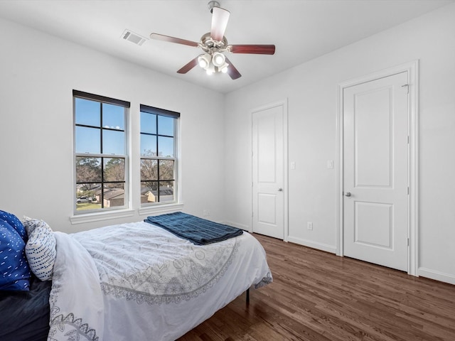 bedroom featuring visible vents, ceiling fan, baseboards, and wood finished floors