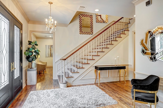 foyer featuring crown molding, french doors, an inviting chandelier, and hardwood / wood-style flooring