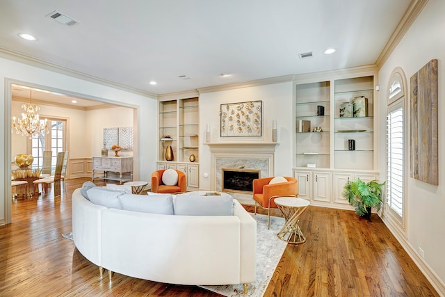 living room with hardwood / wood-style floors, a healthy amount of sunlight, built in features, and a fireplace