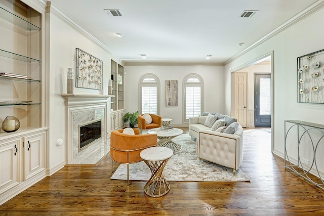 living room with dark hardwood / wood-style flooring, built in features, a fireplace, and ornamental molding