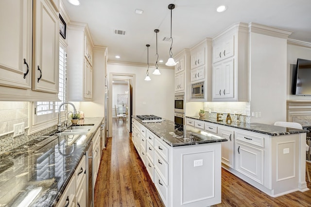 kitchen with pendant lighting, a center island, dark stone counters, sink, and stainless steel appliances