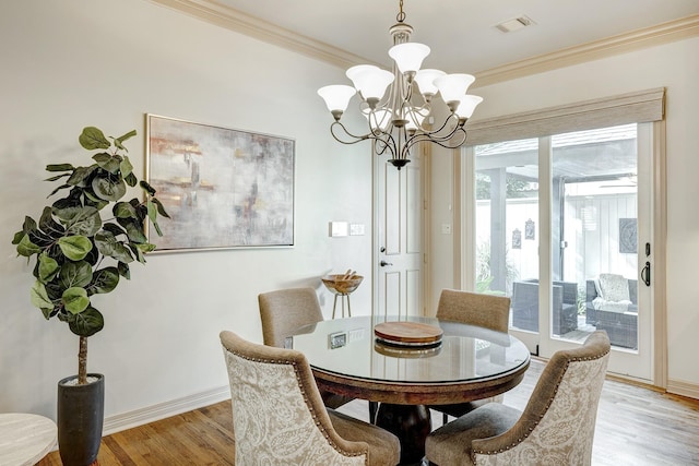 dining area with an inviting chandelier, ornamental molding, and light hardwood / wood-style flooring