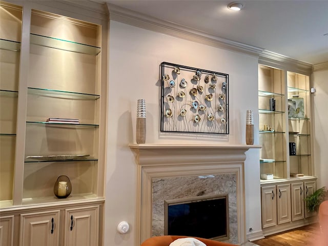 living room featuring light hardwood / wood-style floors, built in features, crown molding, and a premium fireplace