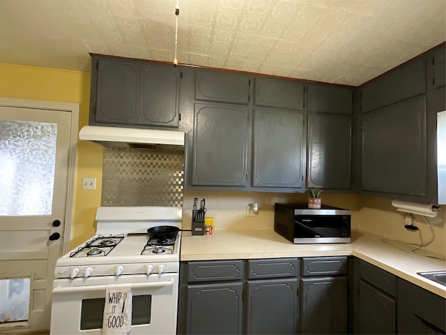 kitchen with gray cabinetry, backsplash, and gas range gas stove