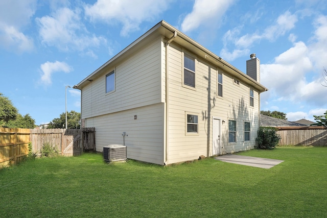 rear view of house with central air condition unit, a patio area, and a yard