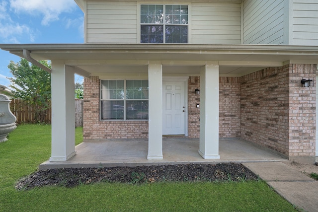 entrance to property with a porch and a lawn