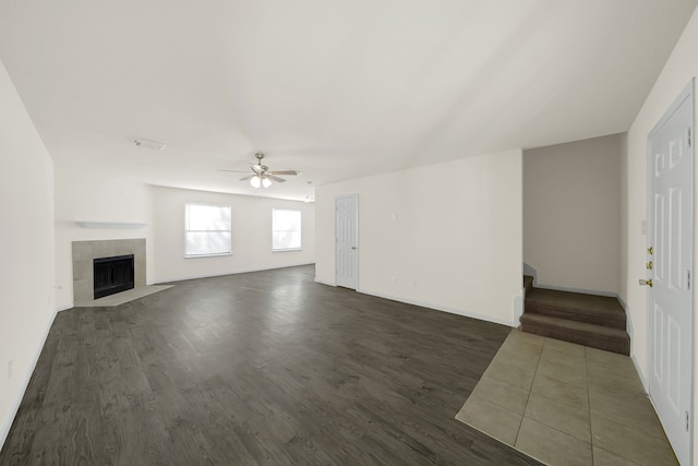 unfurnished living room featuring dark wood-type flooring, a tile fireplace, and ceiling fan