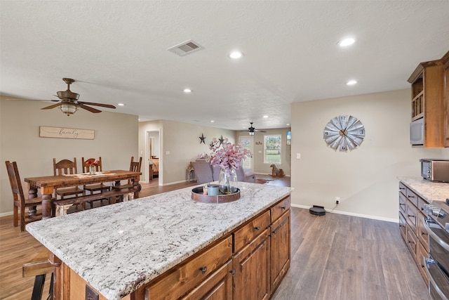 kitchen featuring a textured ceiling, a center island, stainless steel stove, and dark hardwood / wood-style floors