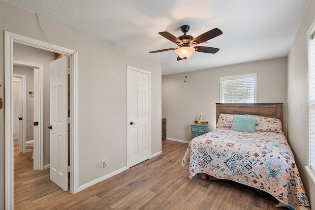 bedroom with ceiling fan, light wood-type flooring, and a textured ceiling