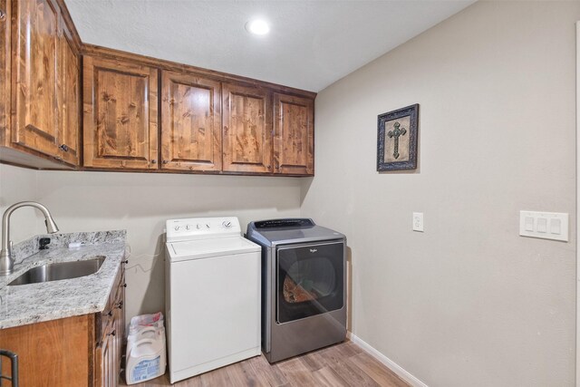 10723 Fm 442nd Rd, Boling, TX 77420 - laundry room with cabinet space, washer and clothes dryer, light wood-type flooring, and baseboards