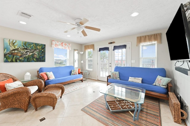 living area featuring light tile patterned flooring, a ceiling fan, visible vents, a textured ceiling, and french doors