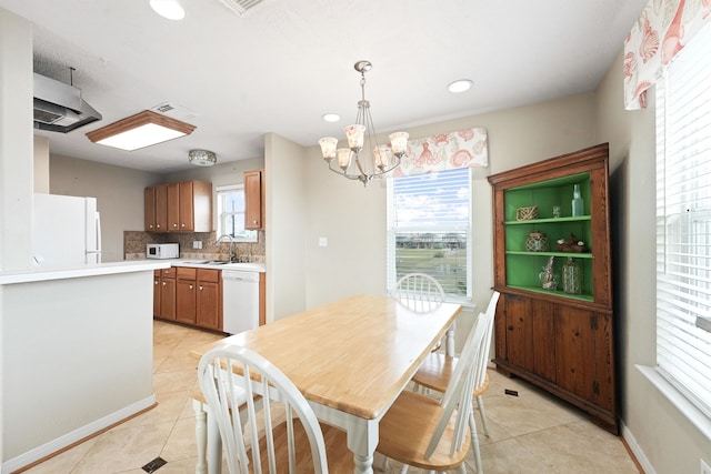 dining area with sink, light tile patterned flooring, and an inviting chandelier