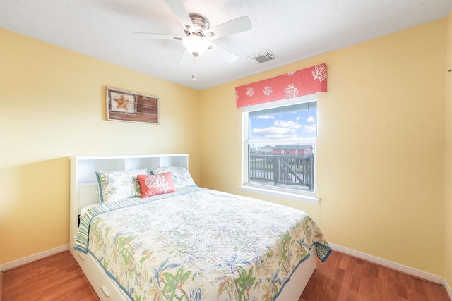 bedroom featuring baseboards, visible vents, wood finished floors, and ceiling fan