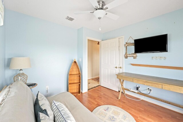 living room with baseboards, visible vents, wood finished floors, and ceiling fan