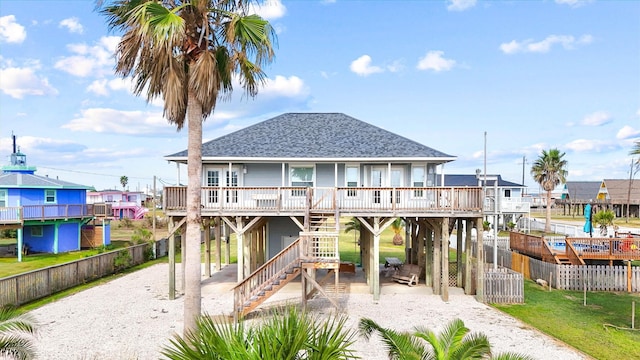 exterior space featuring driveway, a carport, stairs, a shingled roof, and fence