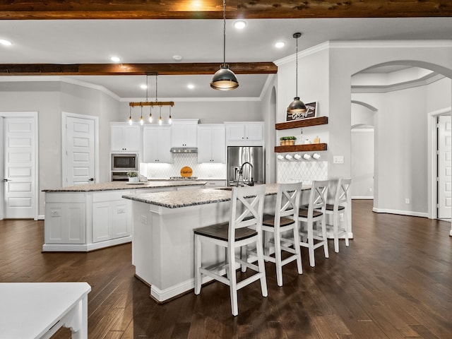 kitchen featuring a kitchen island with sink, pendant lighting, and white cabinets