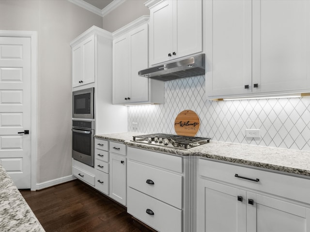 kitchen with appliances with stainless steel finishes, white cabinetry, light stone countertops, and dark wood-type flooring