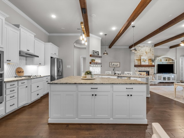 kitchen featuring beam ceiling, appliances with stainless steel finishes, pendant lighting, and a kitchen island with sink