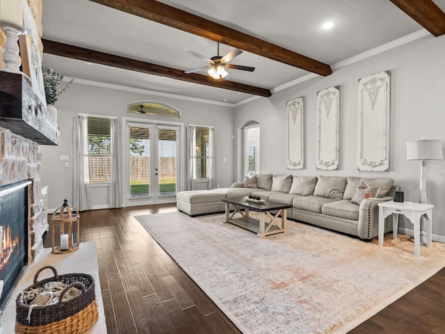 living room featuring crown molding, a stone fireplace, dark hardwood / wood-style flooring, ceiling fan, and beam ceiling